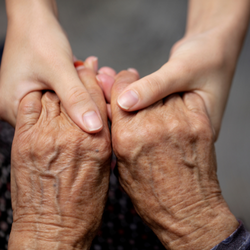 ältere Frau legt Hand in die Hand einer jüngeren