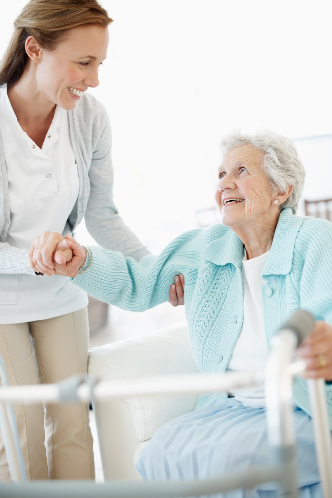 Tochter hilft ihrer älteren Mutter beim Aufstehen, damit sie ihren Rollator benutzen kann